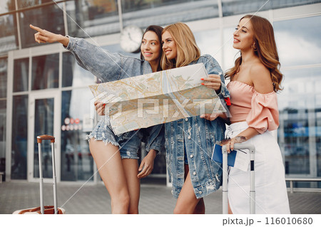 Girls at the airport. Friends with suitcases. Ladies using the map 116010680
