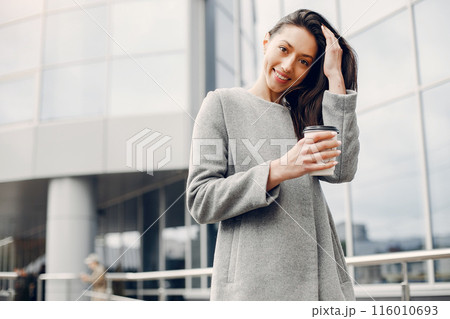 Beautiful girl in a city. Stylish girl near gray building 116010693