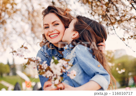 Fashionable mother with daughter. Family in a spring park. Woman in a blue shirt 116010717