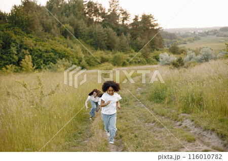 Photo of caucasian mother and two her african american daughters running together. Girls has black curly hair. Mother and daughers wearing white t-shirts. 116010782