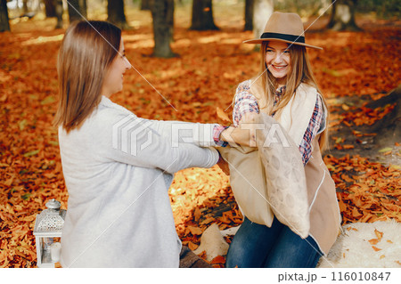 Beautiful girls in a park. Cute ladies in a stylish clothes Beautiful girls in a park. Cute ladies in a stylish clothes 116010847