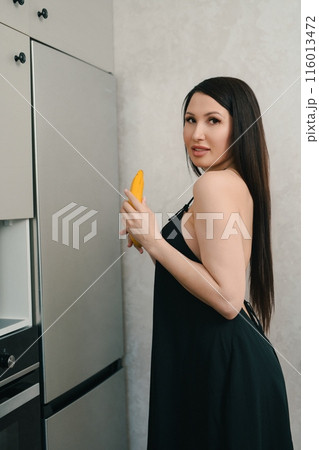 Woman Holding a Mango in a Modern Kitchen 116013472