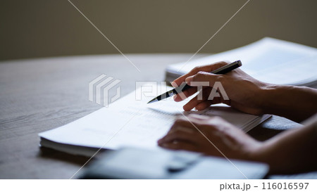Female entrepreneur working to reading document and writing notes while analysis finance of startup 116016597