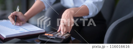 Asian businesswomen using calculator to calculating financial statistics data and checking marketing business document while analyze investment and market stock of new startup in outside office 116016616