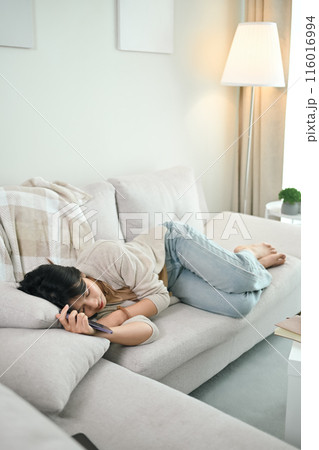 Tired young Asian woman sleeping on comfortable couch at home. Stress free concept Tired young Asian woman sleeping on comfortable couch at home. Stress free concept 116016994