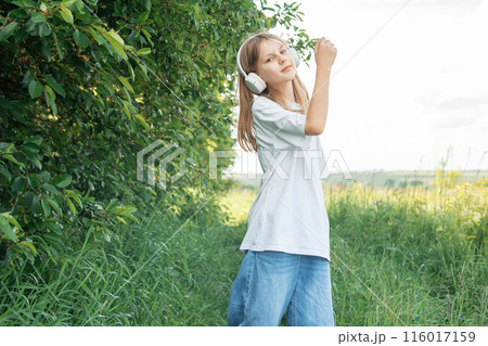 A child  with headphones listening to music and dancing 116017159