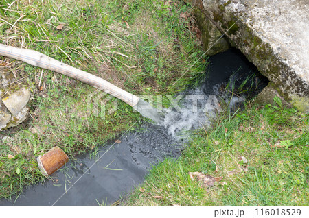 Water flows into the ditch from a hose. Water flows into the ditch from a hose. 116018529