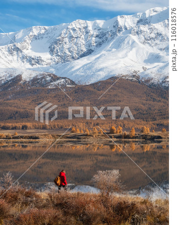 traveler in a red looking to mountain lake in autumn 116018576