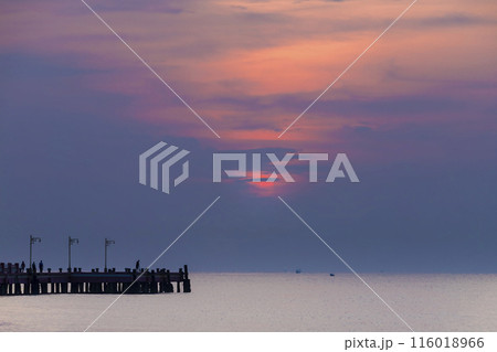 Fiery sky as the sun dips below the horizon, casting a warm glow on beach, sea, or river Fiery sky as the sun dips below the horizon, casting a warm glow on beach, sea, or river 116018966