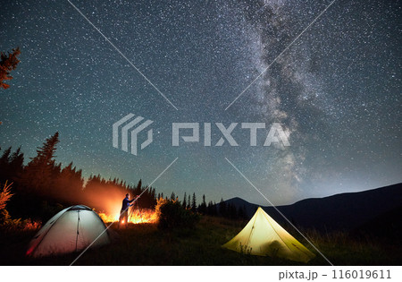 Male photographer taking pictures of Milky way. Man doing photo shoot of starry sky next to his camping. Starry night in mountains. Male photographer taking pictures of Milky way. Man doing photo shoot of starry sky next to his camping. Starry night in mountains. 116019611