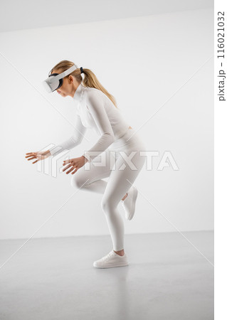 Young woman experiencing virtual reality with VR headset in white plain studio background Young woman experiencing virtual reality with VR headset in white plain studio background 116021032