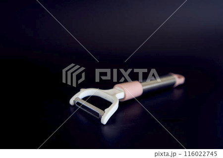 pink vegetable peeler on a black background 116022745