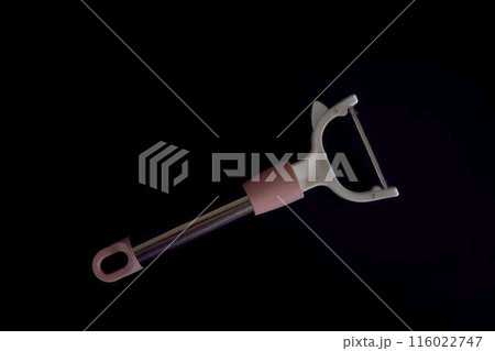 pink vegetable peeler on a black background 116022747