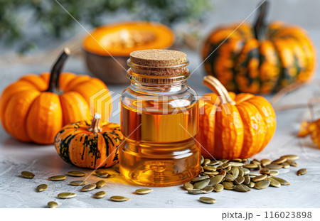 Bottle pumpkin oil surrounded whole pumpkins and pumpkin seeds placed on wooden surface 116023898