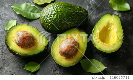 Sliced avocados oil placed on stone surface among green leaves, top view gray table whole avocado 116025711