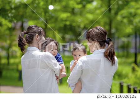 公園で幼児を抱いて談笑する2組の親子 公園で幼児を抱いて談笑する2組の親子 116026128