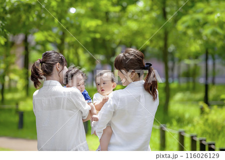公園で幼児を抱いて談笑する2組の親子 公園で幼児を抱いて談笑する2組の親子 116026129