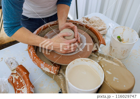 An experienced potter uses potter wheel to create bowl from wet soft clay An experienced potter uses potter wheel to create bowl from wet soft clay 116029747
