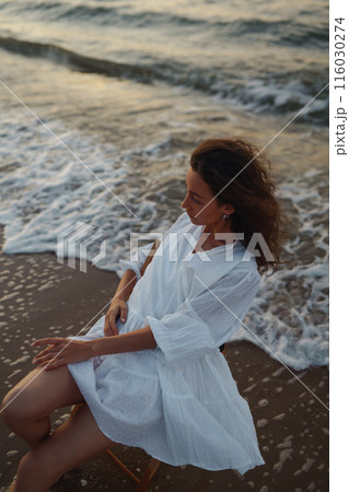 Stylish woman in elegant white dress posing near the sea. People, freedom, lifestyle, travel. 116030274