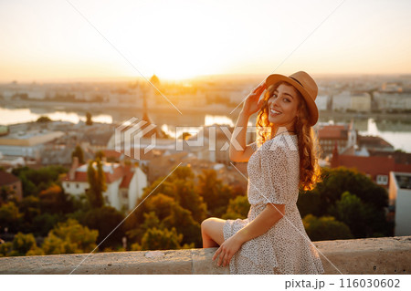 Portrait of happy tourist in hat at dawn enjoys cityscape. Traveling in Europe. Concept tourism. 116030602