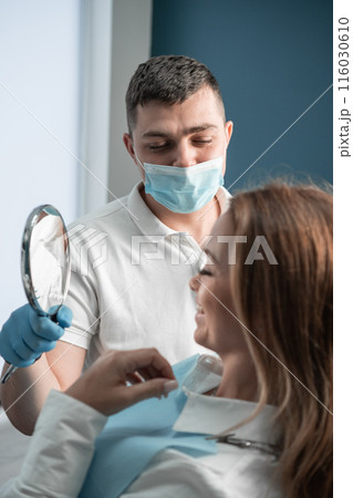 In a dental clinic, the patient rests in a chair, looks in the mirror at the result of work and dental treatment, relying on the experience and qualifications of the doctor who performs the treatment. In a dental clinic, the patient rests in a chair, looks in the mirror at the result of work and dental treatment, relying on the experience and qualifications of the doctor who performs the treatment. 116030610
