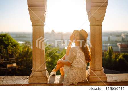Young female tourist enjoys the view of the city at sunset. Travel and tourism concept. 116030611
