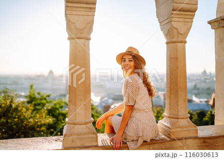 Young female tourist enjoys the view of the city at sunset. Travel and tourism concept. 116030613