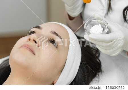 A woman is enjoying a facial mask at a beauty clinic, improving skin health and offering a luxurious skincare experience for overall wellbeing. The treatment provides relaxation and rejuvenation A woman is enjoying a facial mask at a beauty clinic, improving skin health and offering a luxurious skincare experience for overall wellbeing. The treatment provides relaxation and rejuvenation 116030662
