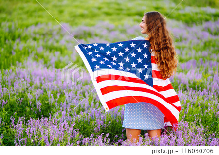 Young woman with american USA flag on blooming meadow. Independence Day, 4th July. 116030706