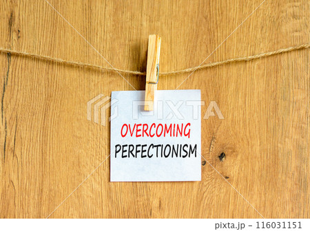 Overcoming perfectionism symbol. Concept words Overcoming perfectionism on beautiful white paper on clothespin. Beautiful wooden background. Business Overcoming perfectionism concept. Copy space. 116031151