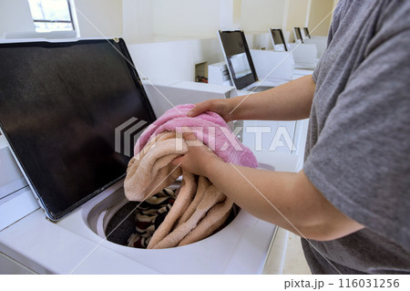 An attendant washes towels at laundromat with washing machine 116031256