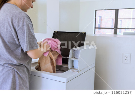 An employee of laundromat washes towels in washing machine 116031257