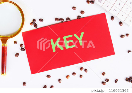 The text KEY on a red card on a white background in a composition with coffee beans and a magnifying glass 116031565