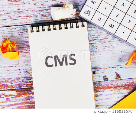 Business concept. CMS - short for Content Management System in a notebook next to a calculator and crumpled stickers on the boards Business concept. CMS - short for Content Management System in a notebook next to a calculator and crumpled stickers on the boards 116031570