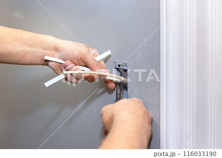 During renovations, electrician connects an electrical outlet to wall of home electrical system 116033190