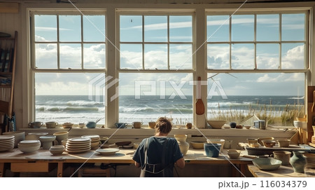A serene coastal studio with sea-view windows where a potter crafts marine-themed ceramics. 116034379