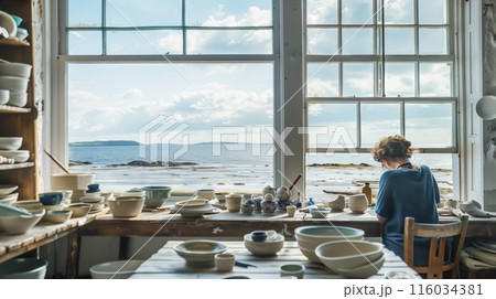 A tranquil coastal studio with large windows. A potter crafts marine-themed ceramics inspired by the sea. 116034381