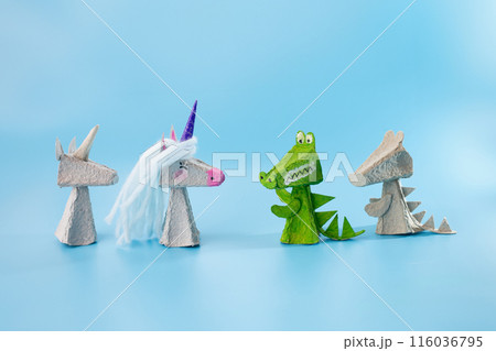 Crafted toy animals standing next to each other: unicorn, alligator, miniature figurine. Several character designs in a fairy tale scene featuring finger toys made from recycled materials, DIY 116036795