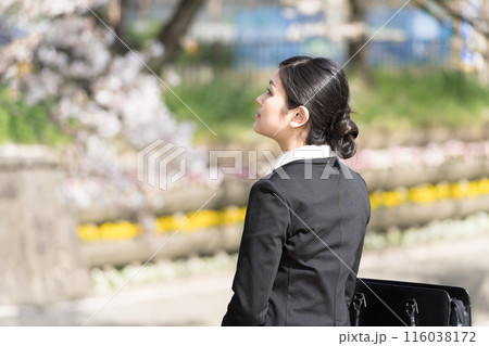 並木の川沿いで桜を眺めている若いビジネスウーマン 並木の川沿いで桜を眺めている若いビジネスウーマン 116038172