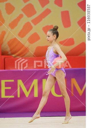 A young rhythmic gymnast performs with a ball at a competition, showcasing her skills and talent A young rhythmic gymnast performs with a ball at a competition, showcasing her skills and talent 116038587