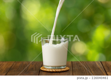 milk pouring into glass on wooden table 116040461