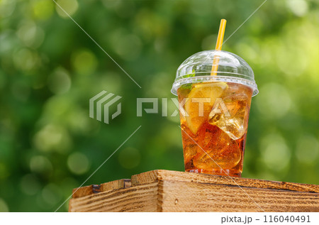 iced tea with lemon in disposable plastic glass on wooden table 116040491