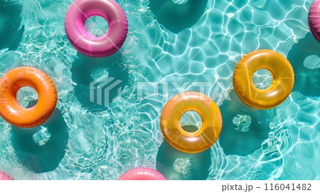 Top-view of a pool with vibrant swimming rings, lit by natural light for a lively, refreshing vibe. 116041482