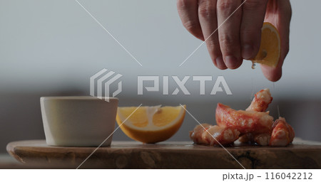 man squeeze lemon on crab on olive wood board 116042212