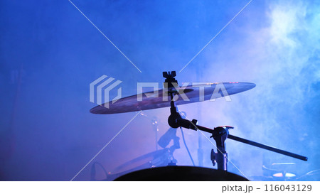 A drum set takes center stage, bathed in blue lights, ready for a rhythmic performance in a music venue. 116043129