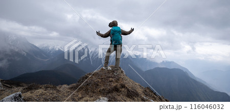 Woman hiker enjoy the view on mountain top cliff edge face the snow capped mountains in tibet 116046032