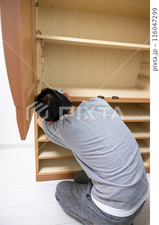 移動した和箪笥のネジを止めて組み立てている男性 116047299