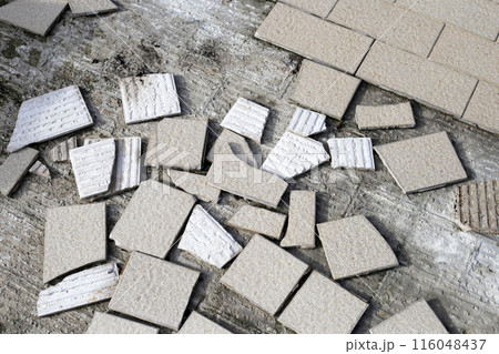 Cracked brown tiles on cement floor 116048437