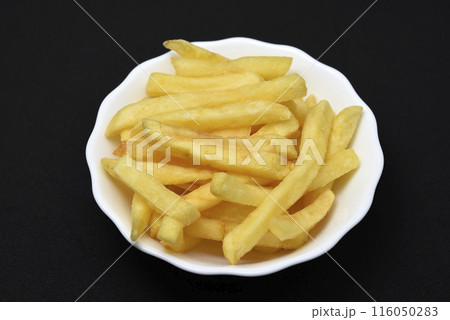 French fries in a white plate on a black background. Delicious fried potatoes. French fries in a white plate on a black background. Delicious fried potatoes. 116050283
