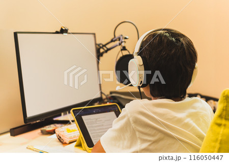 Young student study online at home using PC computer and headphone. 116050447
